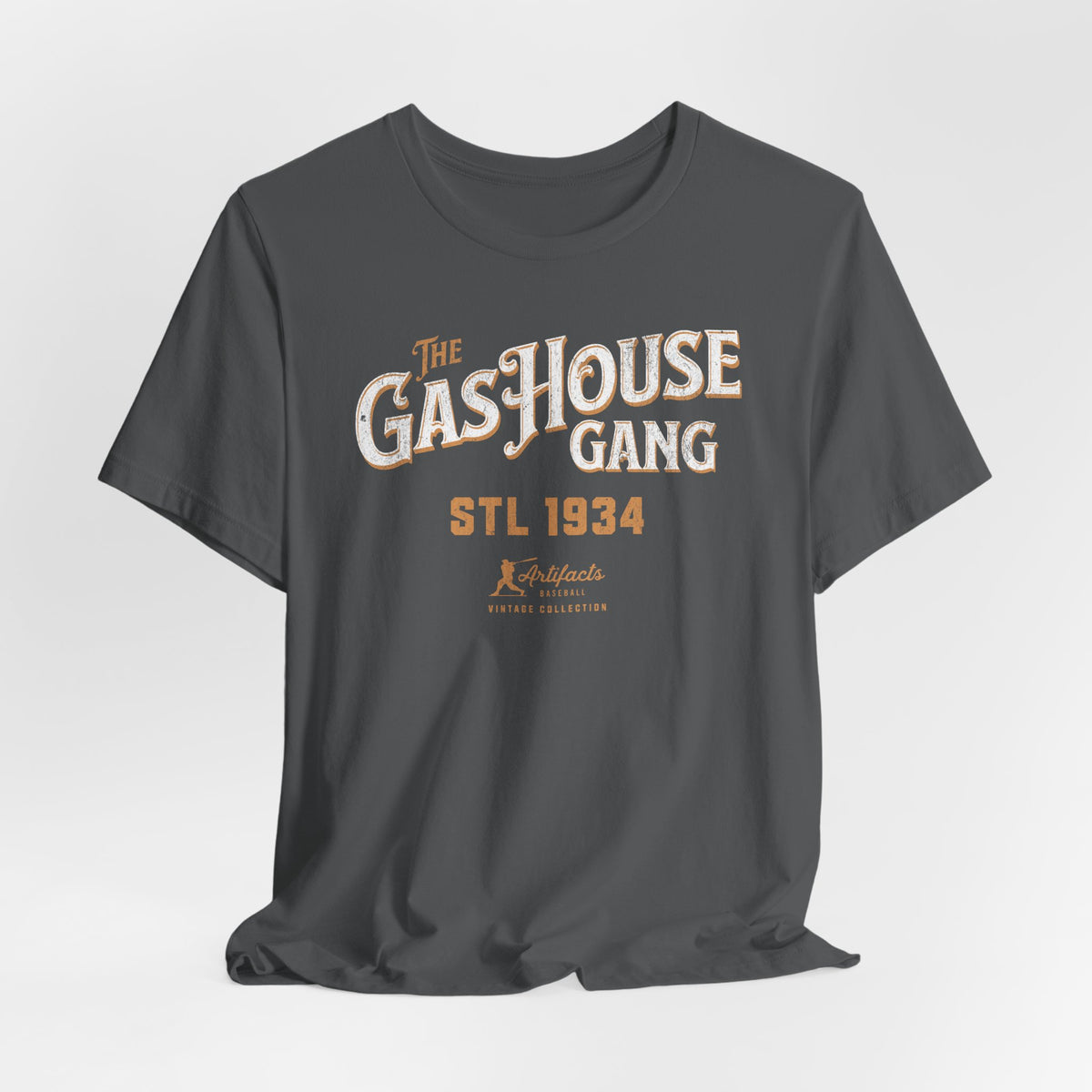 An asphalt grey short-sleeve t-shirt with a vintage-style graphic print reading 'The Gas House Gang STL 1934' and a small 'Artifacts Collection' logo.