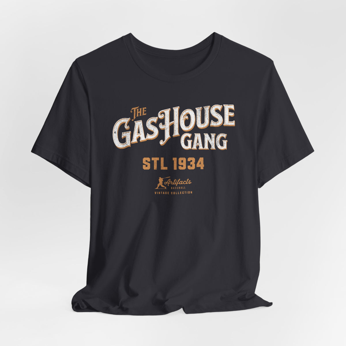 A dark grey short-sleeve t-shirt with a vintage-style graphic print reading 'The Gas House Gang STL 1934' and a small 'Artifacts Collection' logo.