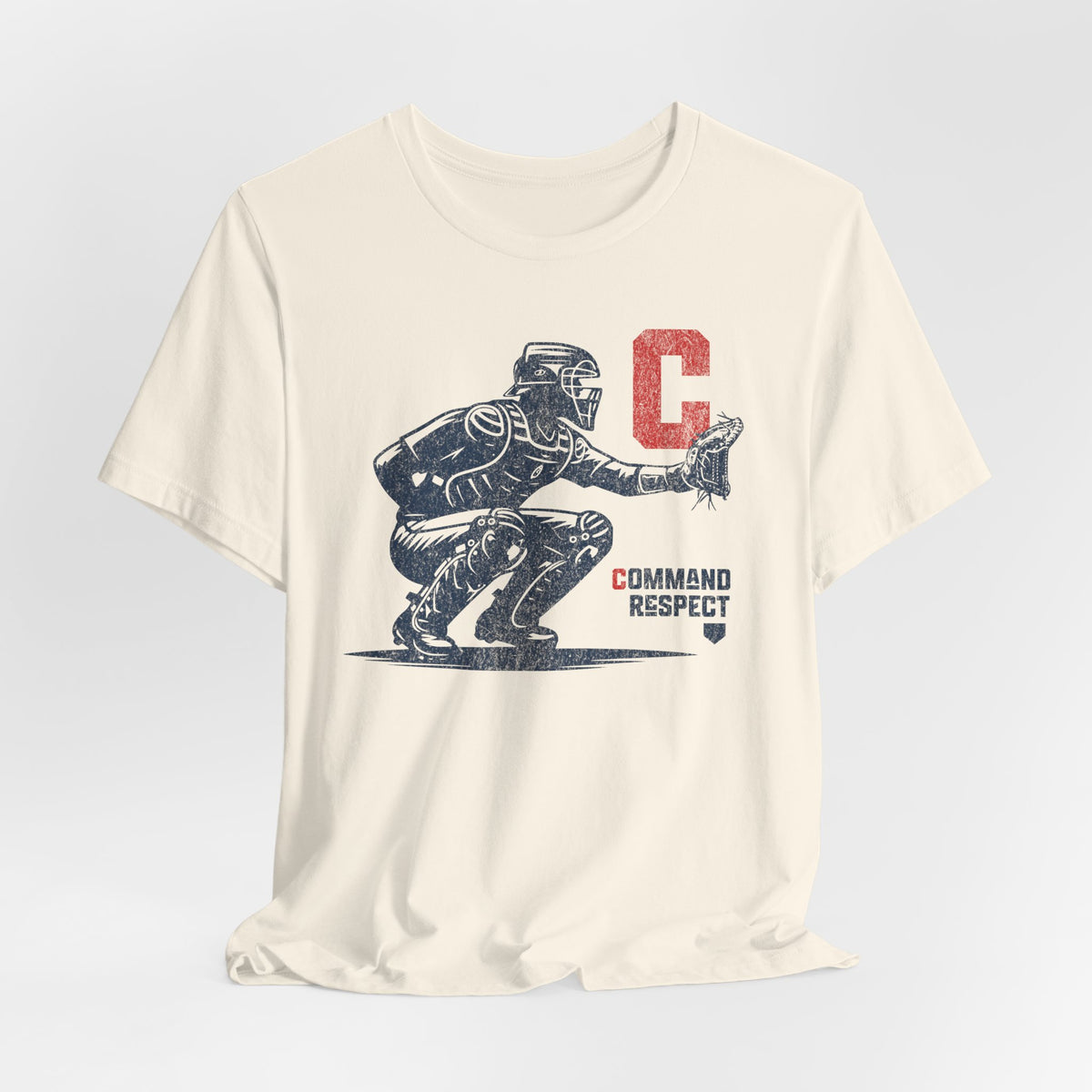 A natural (off-white) t-shirt featuring a baseball catcher and the words COMMAND RESPECT in navy, and a red letter C.