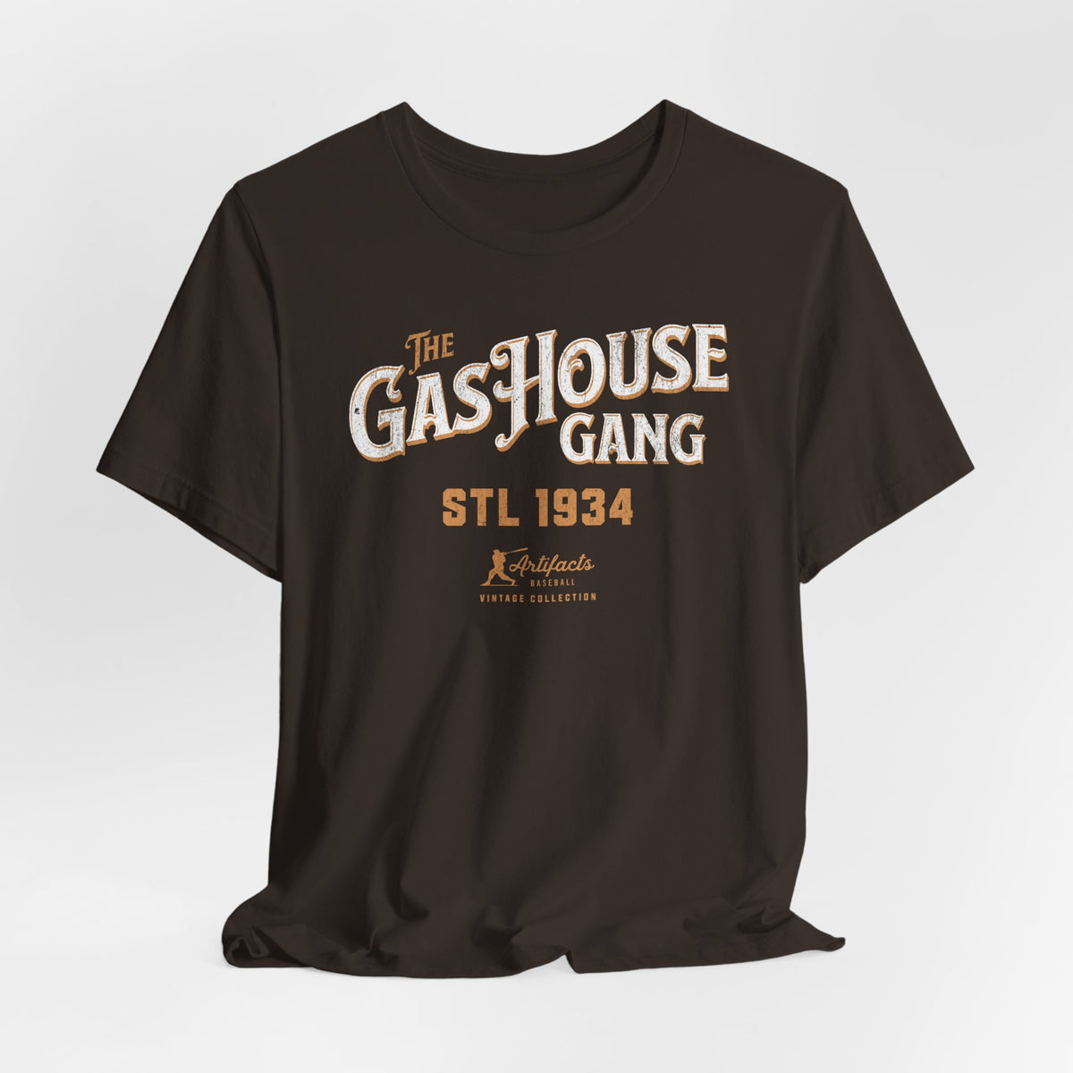 A dark brown short-sleeve t-shirt with a vintage-style graphic print reading 'The Gas House Gang STL 1934' and a small 'Artifacts Collection' logo.