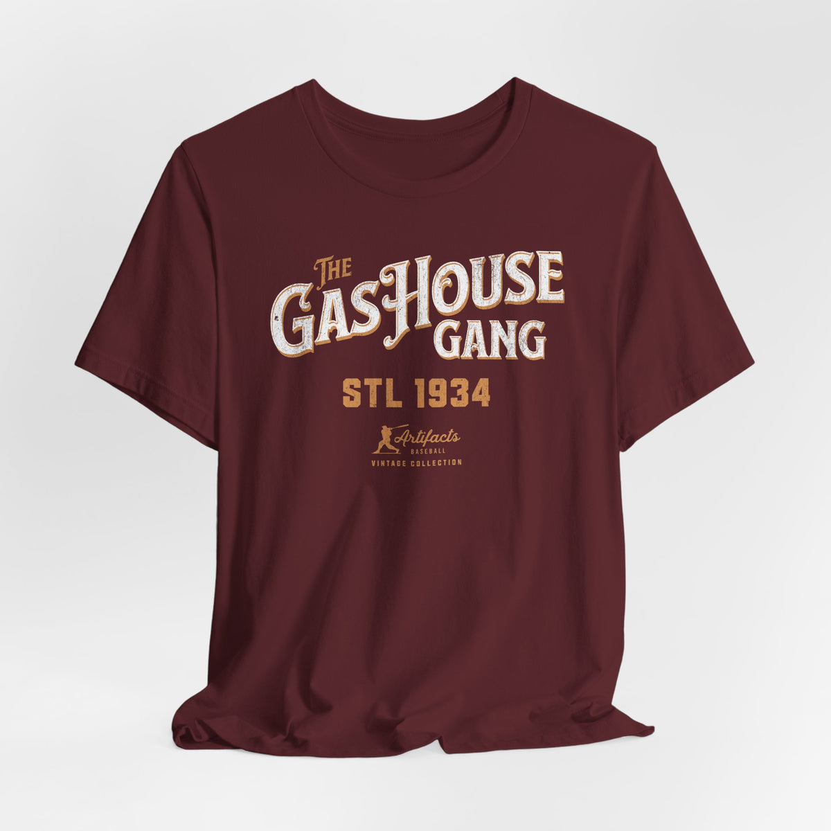 A maroon short-sleeve t-shirt with a vintage-style graphic print reading 'The Gas House Gang STL 1934' and a small 'Artifacts Collection' logo.